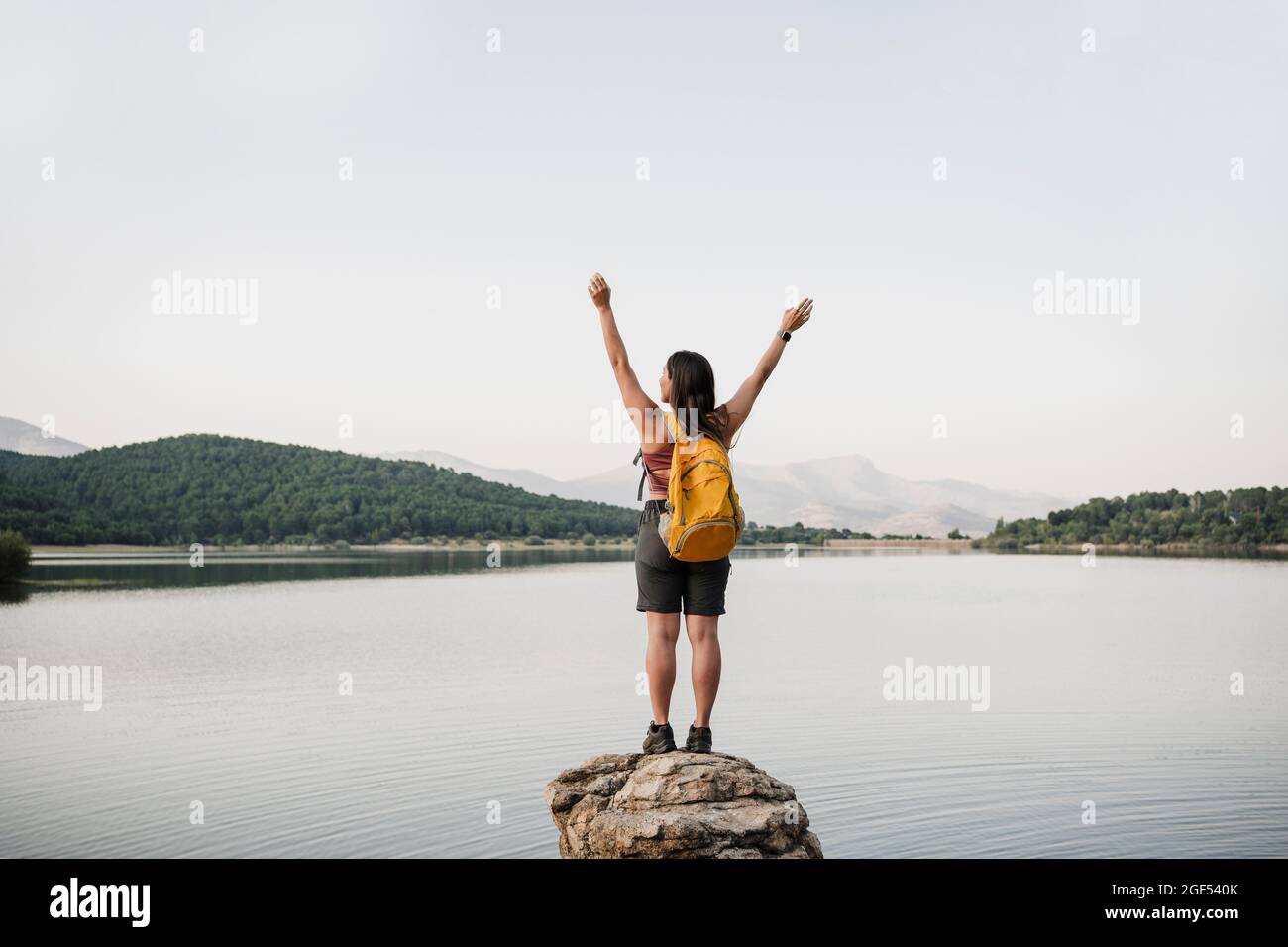 Spensierate escursionista femminile con braccia sollevate in piedi sulla roccia durante la vacanza Foto Stock