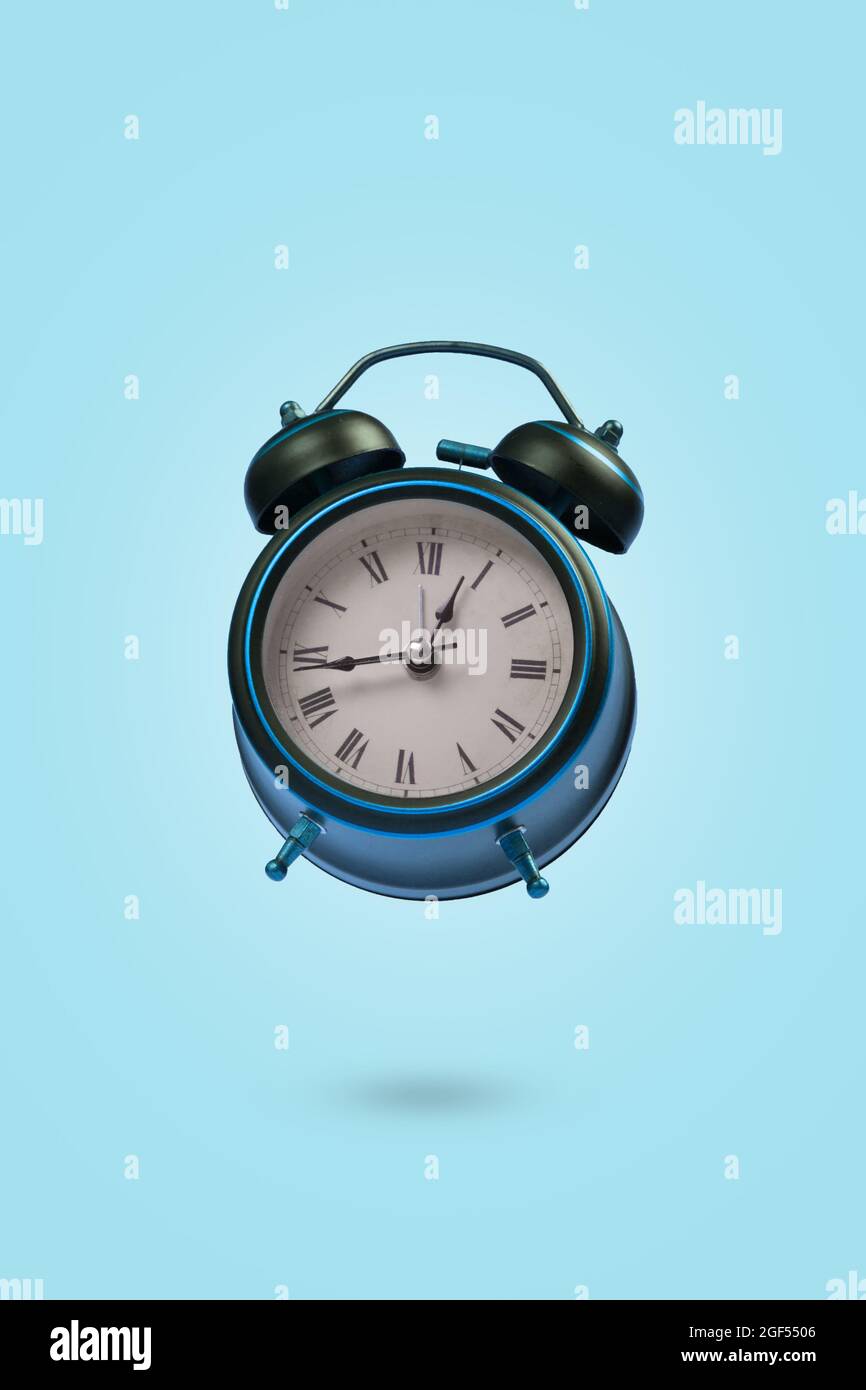 Scena minimale con una sveglia che galleggia in aria su sfondo blu. Concetto creativo del tempo. Spazio di copia. Foto Stock