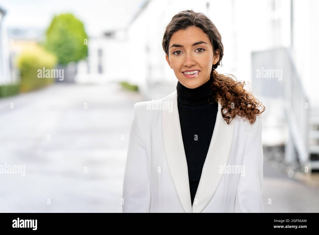 Sorridente giovane donna professionista con blazer bianco Foto Stock