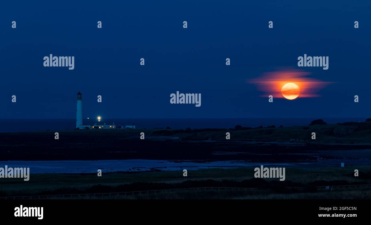 Dunbar, East Lothian, Scozia, Regno Unito, 23 agosto 2021. UK Meteo: Moonrise. Una vista della luna piena di agosto conosciuta come la luna Sturgeon stasera sopra l'orizzonte nel cielo notturno al faro di Barns Ness. Foto Stock