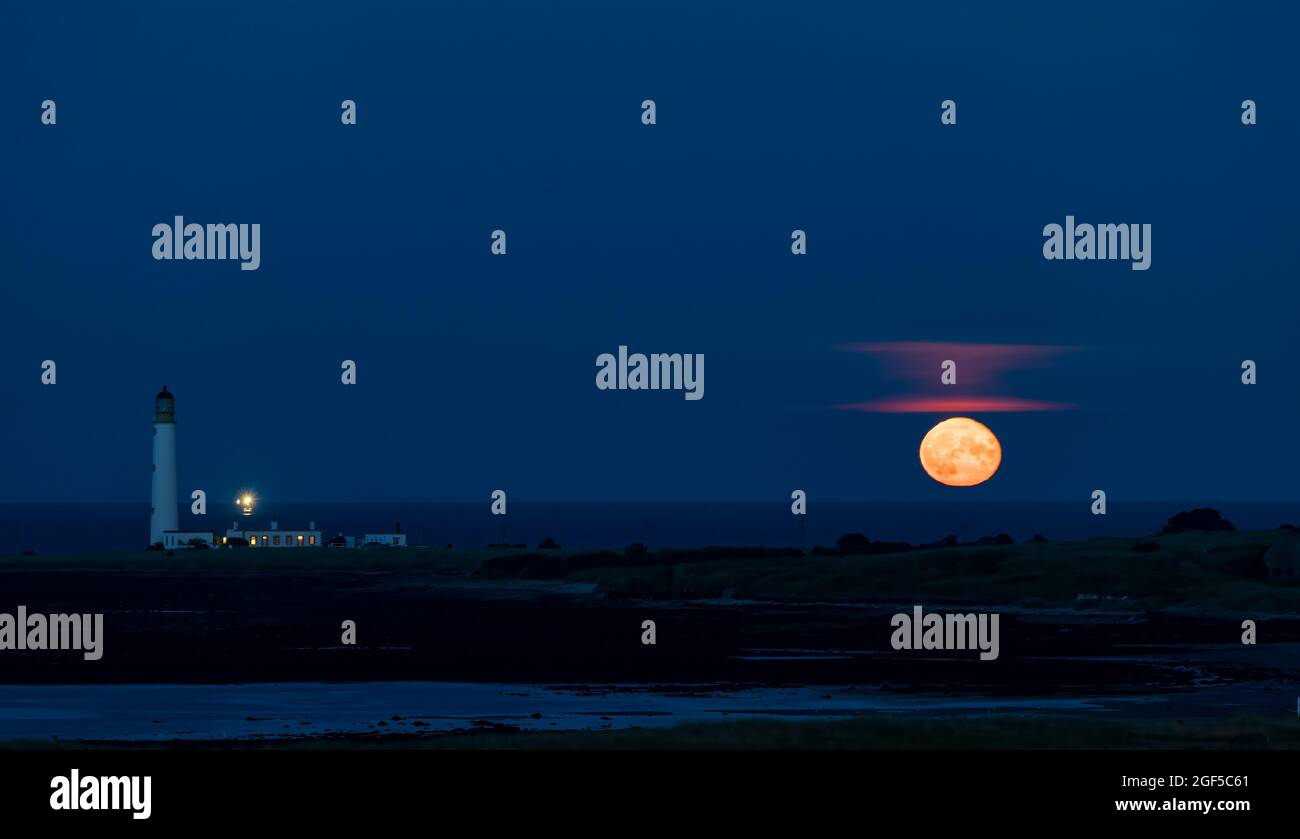 Dunbar, East Lothian, Scozia, Regno Unito, 23 agosto 2021. UK Meteo: Moonrise. Una vista della luna piena di agosto conosciuta come la luna Sturgeon stasera sopra l'orizzonte nel cielo notturno al faro di Barns Ness. Foto Stock