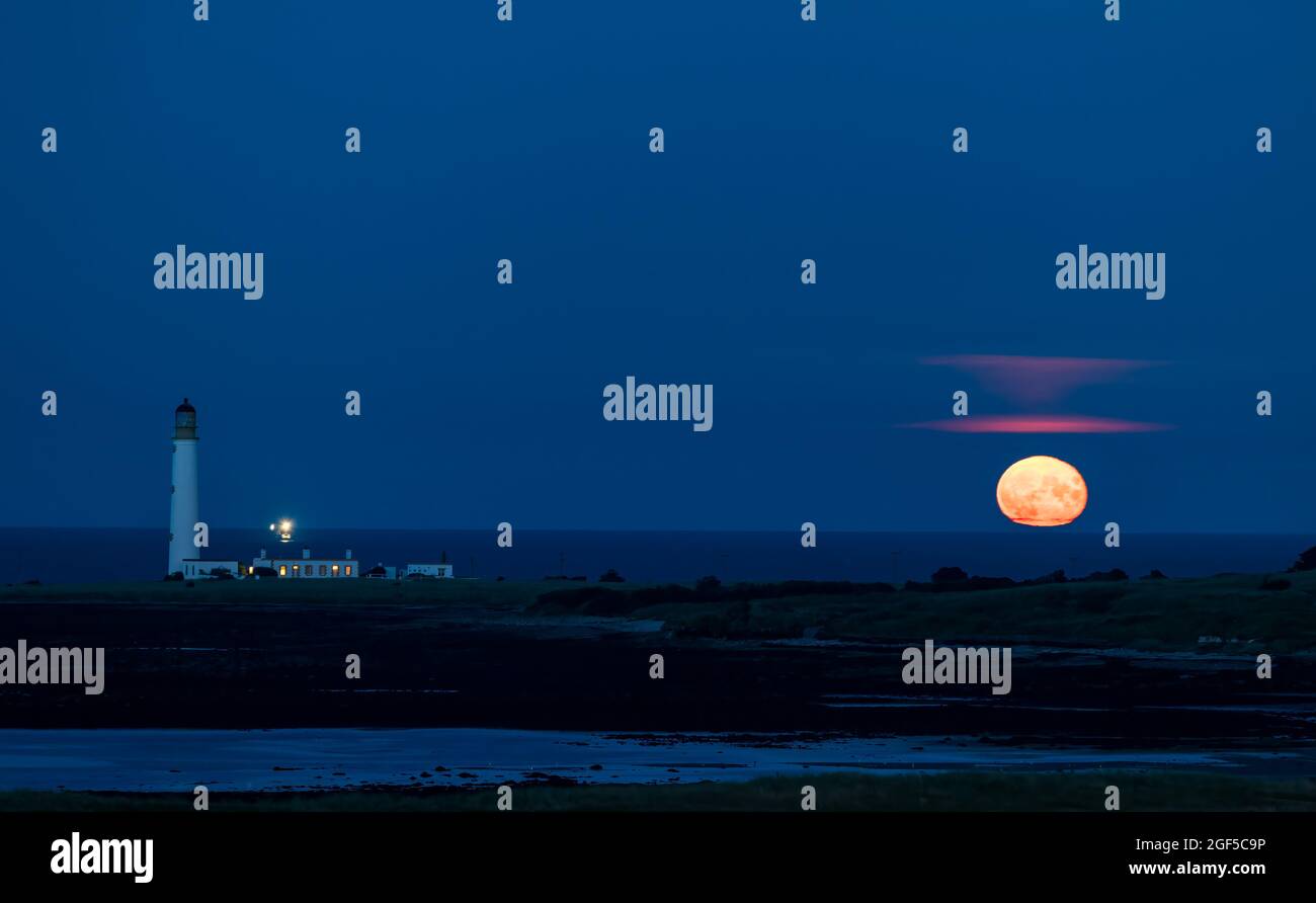 Dunbar, East Lothian, Scozia, Regno Unito, 23 agosto 2021. UK Meteo: Moonrise. Una vista della luna piena di agosto conosciuta come la luna Sturgeon stasera sopra l'orizzonte nel cielo notturno al faro di Barns Ness. Foto Stock