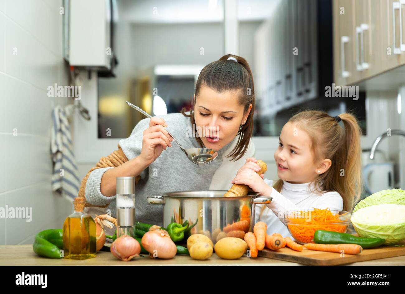 Buona madre e figlia piccola degustazione zuppa insieme Foto Stock