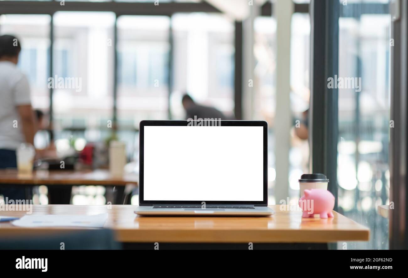 Computer portatile con schermo vuoto sulla scrivania, risparmio di denaro con rosa Piggy Bank. Foto Stock