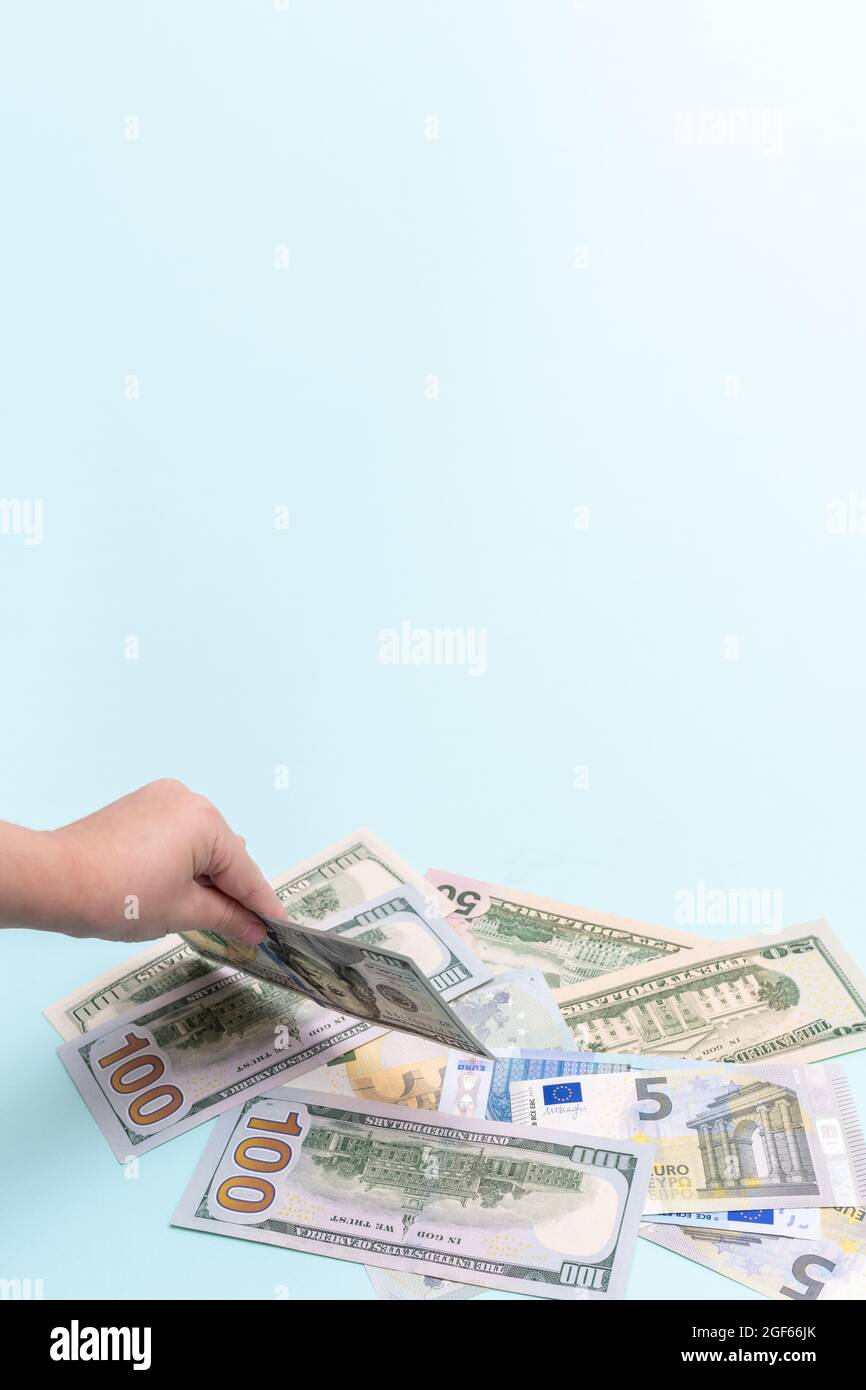 Mano del bambino che tiene una fattura del cento dollaro, cornice verticale, spazio di copia. Costo di allevare un bambino. Foto Stock