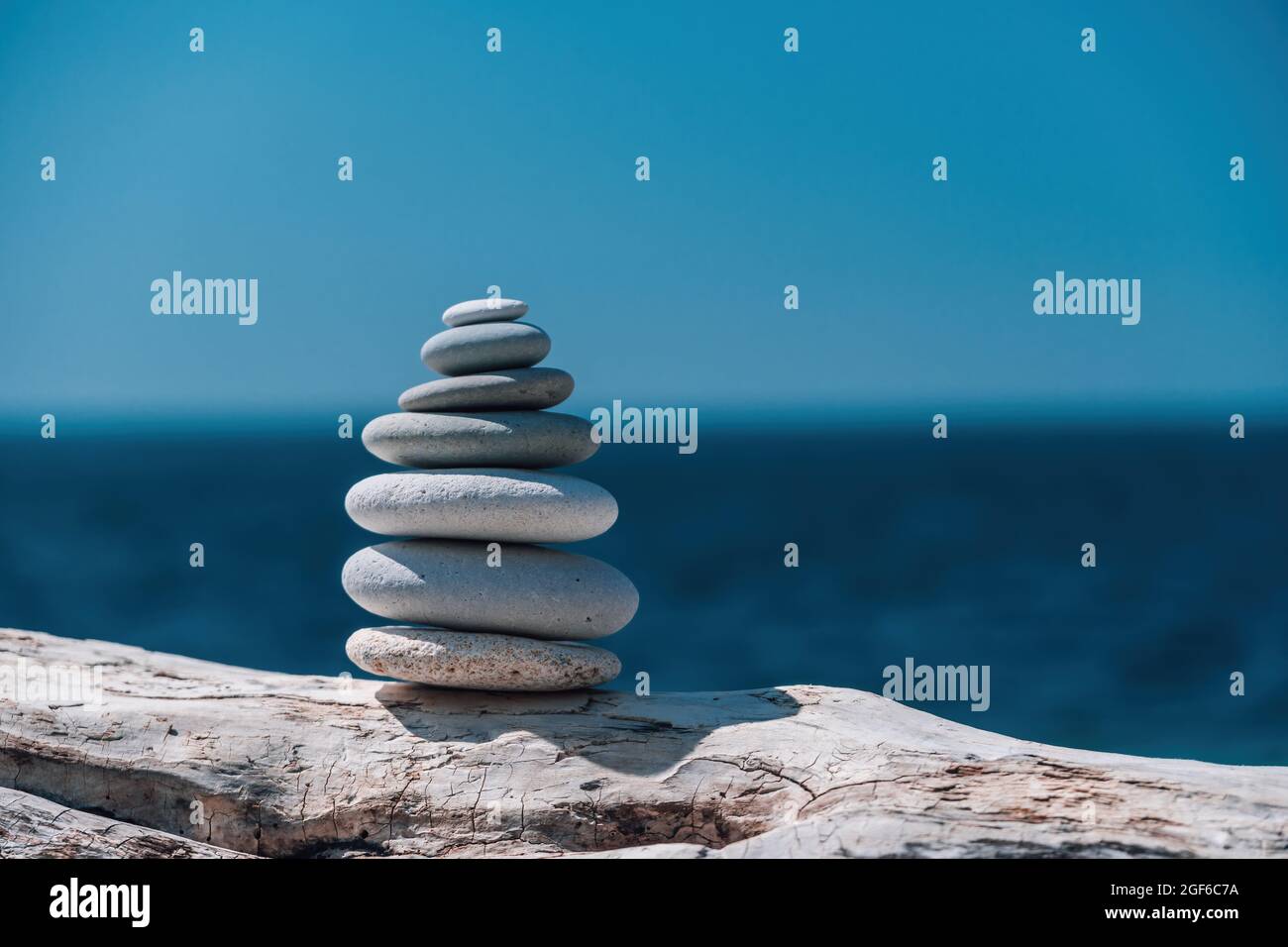 Equilibrata piramide di ciottoli sulla spiaggia in una giornata di sole. Abstract Sea bokeh sullo sfondo. Messa a fuoco selettiva. Pietre Zen sulla spiaggia di mare, meditazione Foto Stock