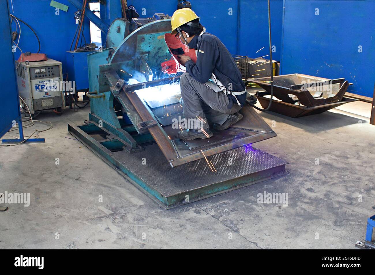 Una saldatrice utilizza una saldatrice elettrica ad arco in un'officina di fabbricazione. Foto Stock