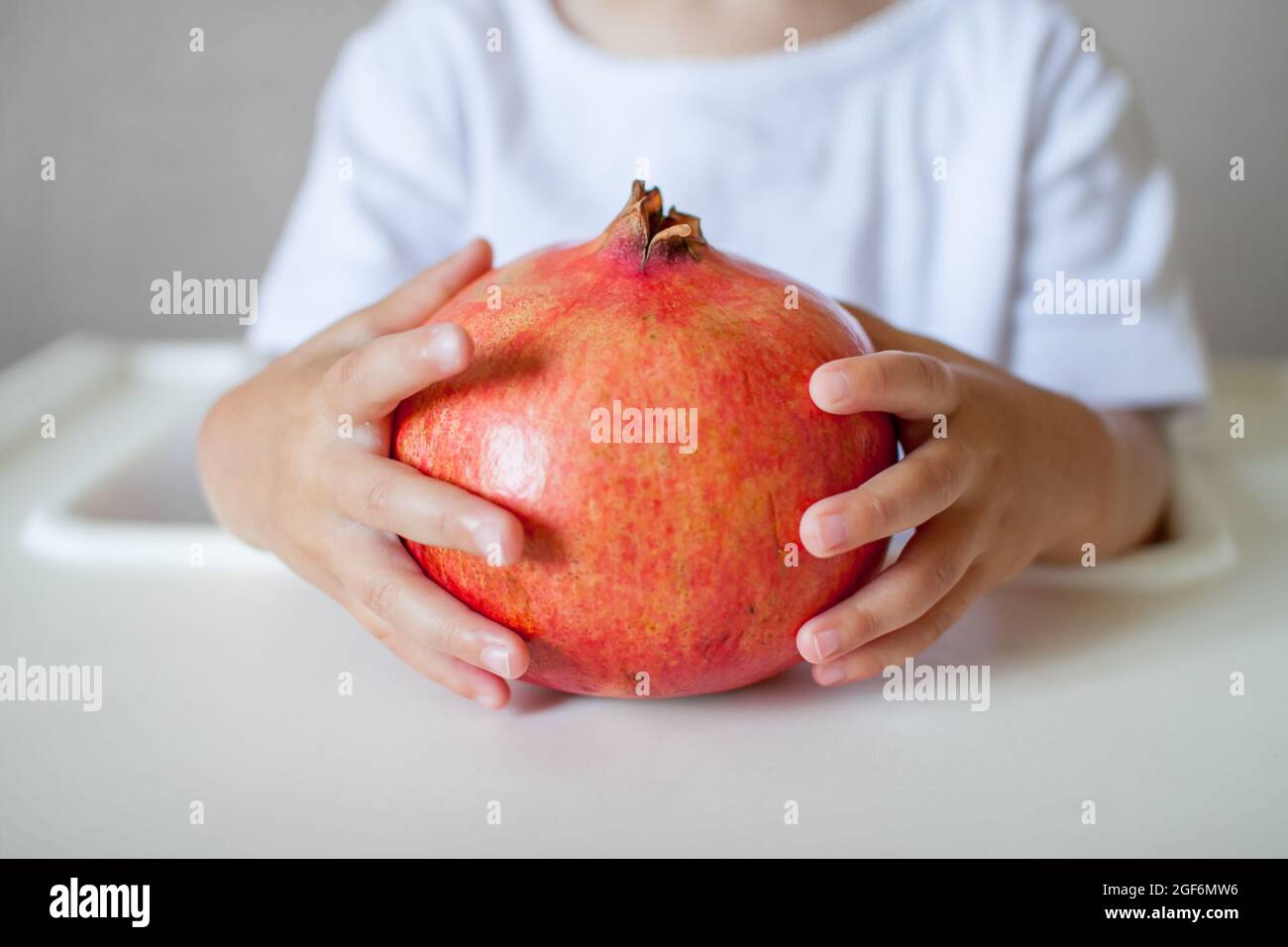 Pomegranate la frutta nelle mani di un bambino piccolo primo piano. Il simbolo del nuovo anno ebraico. Rosh Hashana. Foto Stock