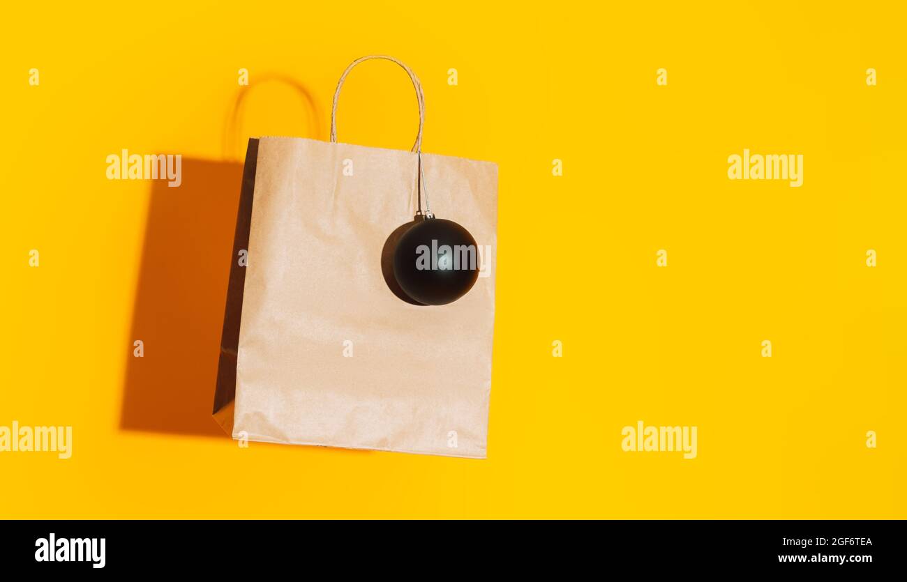 Sacchetto di carta con bauble nero opaco su sfondo giallo Foto Stock