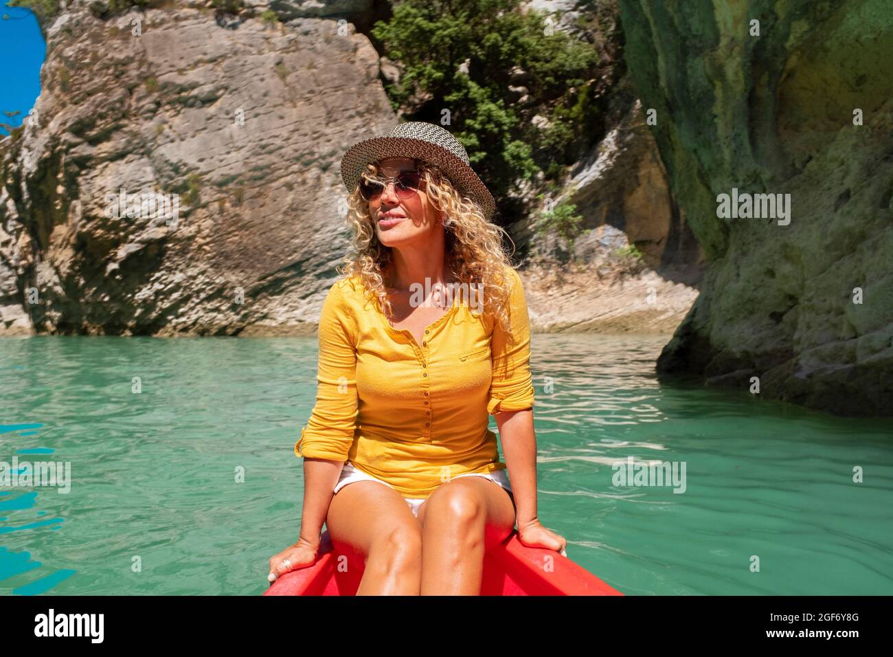 Felice donna viaggiatore lifestyle seduta e godere su una canoa rossa in bellissimo canyon con fiume verde acqua - gioiosa gente libera si divertono Foto Stock
