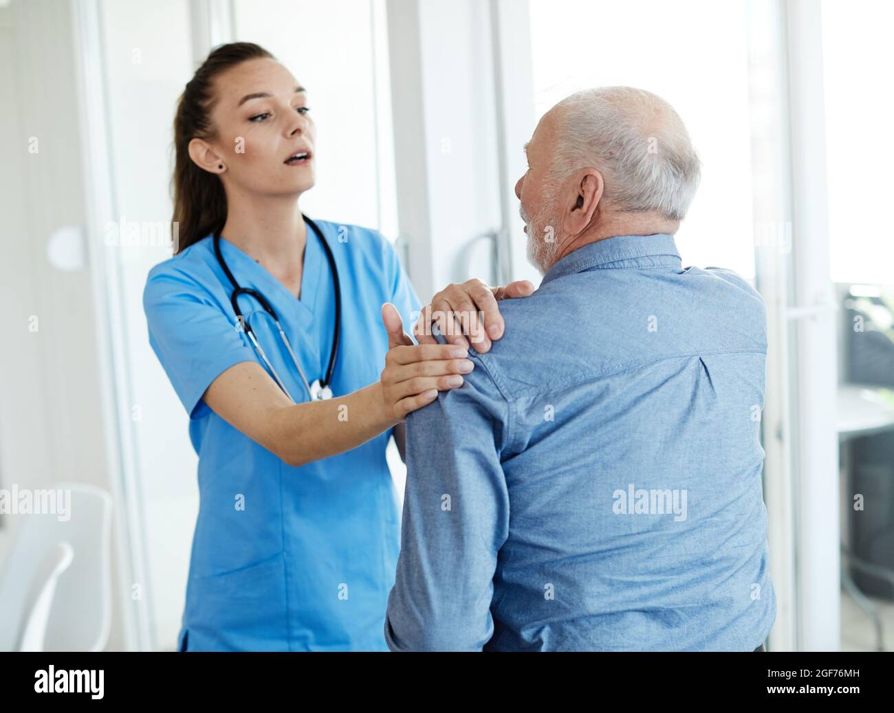 infermiera medico assistenza senior aiuto assistenza pensionamento casa dolore schiena spalla mal Foto Stock