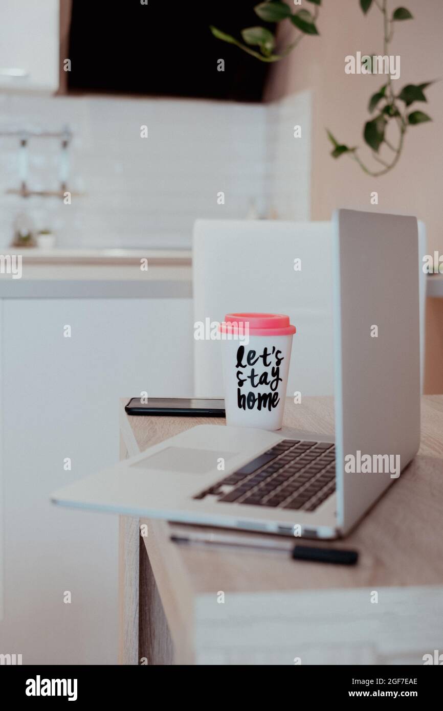 Orientamento verticale per lavorare da casa. Vista su un computer portatile da cucina e una tazza da caffè Foto Stock