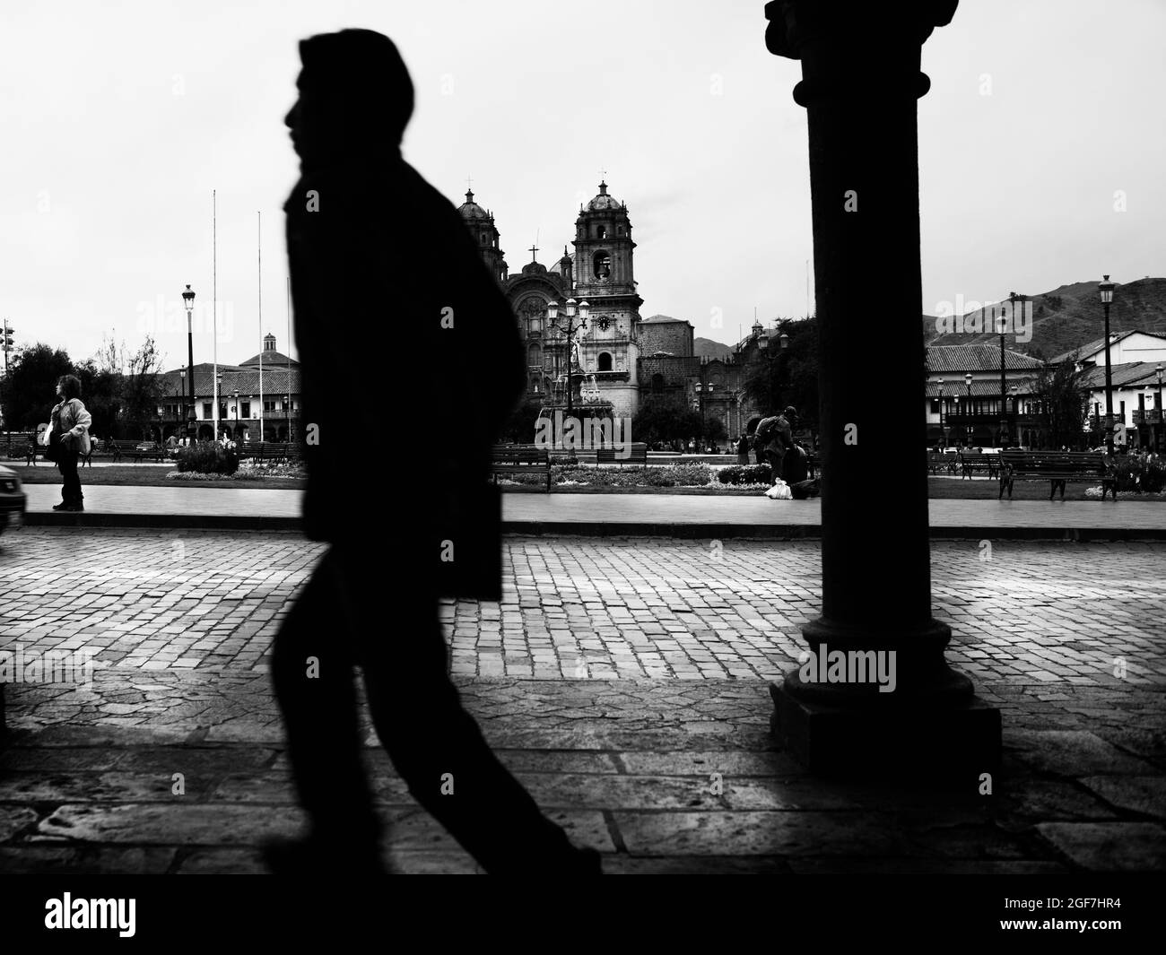 Silhouette dell'uomo che cammina attraverso la piazza della città. Bianco e nero Foto Stock