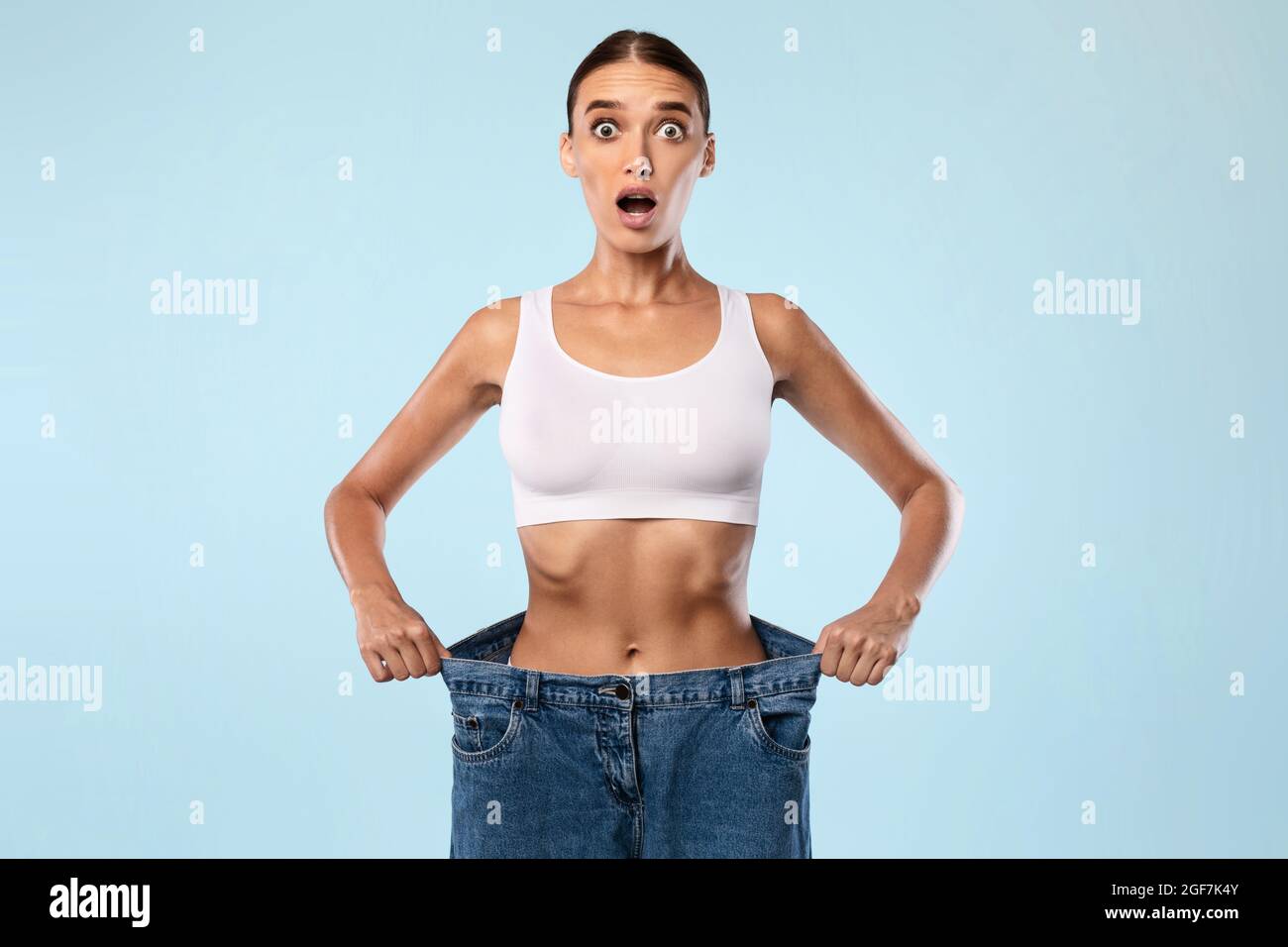 Shocked Skinny Woman tirando il suo vecchio grande jeans sciolti Foto Stock