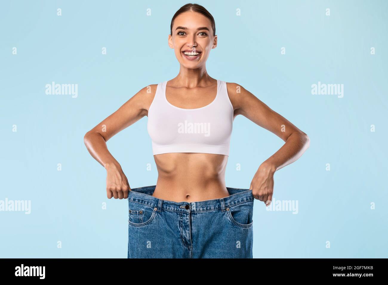 Donna tirando il suo vecchio grande jeans sciolti e in posa Foto Stock