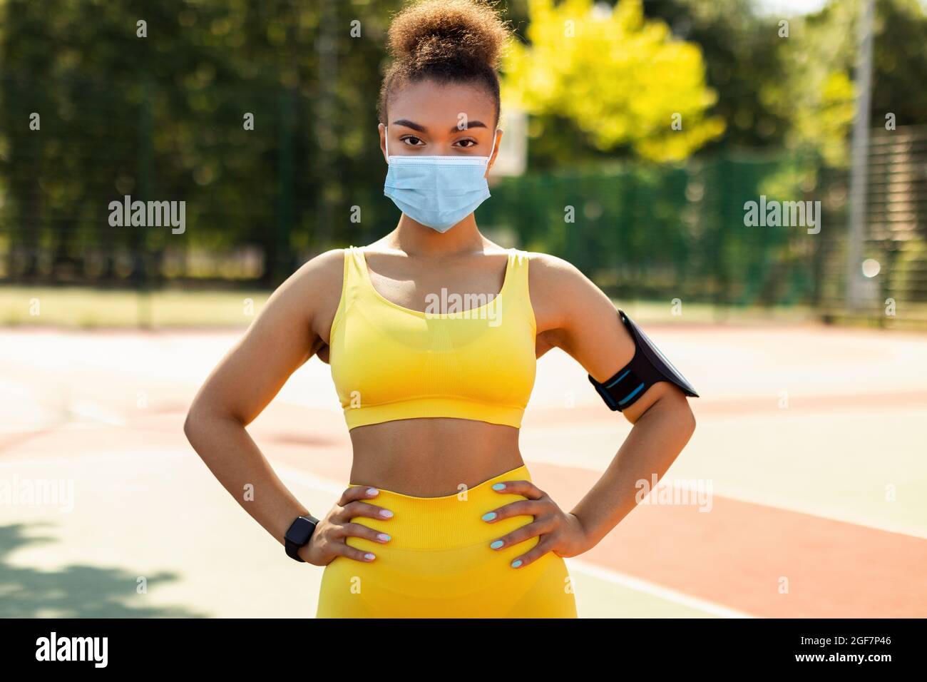 Donna che indossa maschera protettiva e sportswear posa Foto Stock