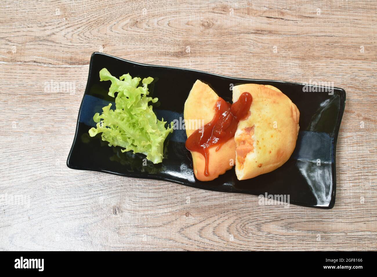 pane ripieno di salsiccia di pollo affumicata e formaggio ketchup condito con verdure sul piatto Foto Stock