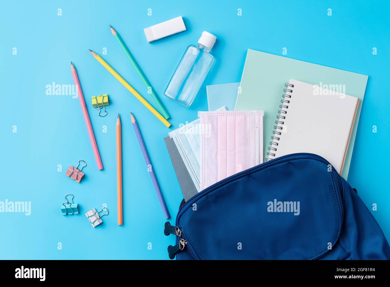 Vista dall'alto dello zaino blu con cancelleria da scuola su sfondo blu, concetto di design di ritorno a scuola. Foto Stock