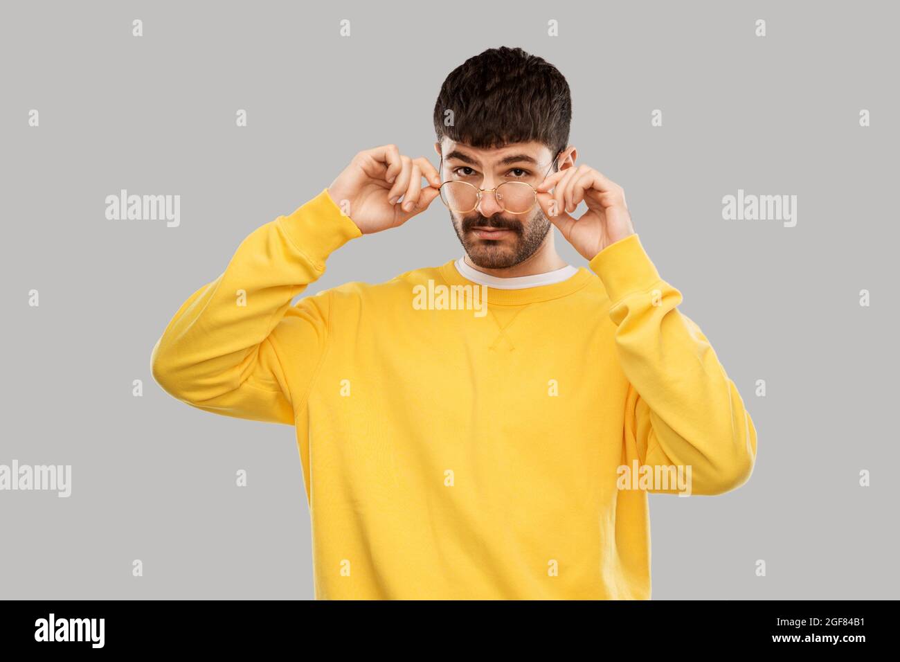 giovane uomo in occhiali e felpa gialla Foto Stock