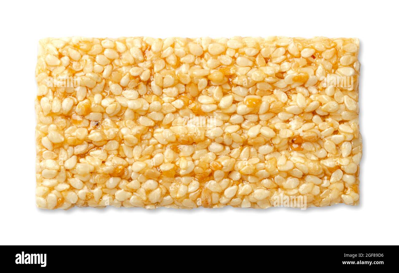 Barra fragile di sesamo, dall'alto, su sfondo bianco. Una barra di caramelle di semi di sesamo, chiamata anche crunch, una confezione di semi di sesamo e miele. Foto Stock