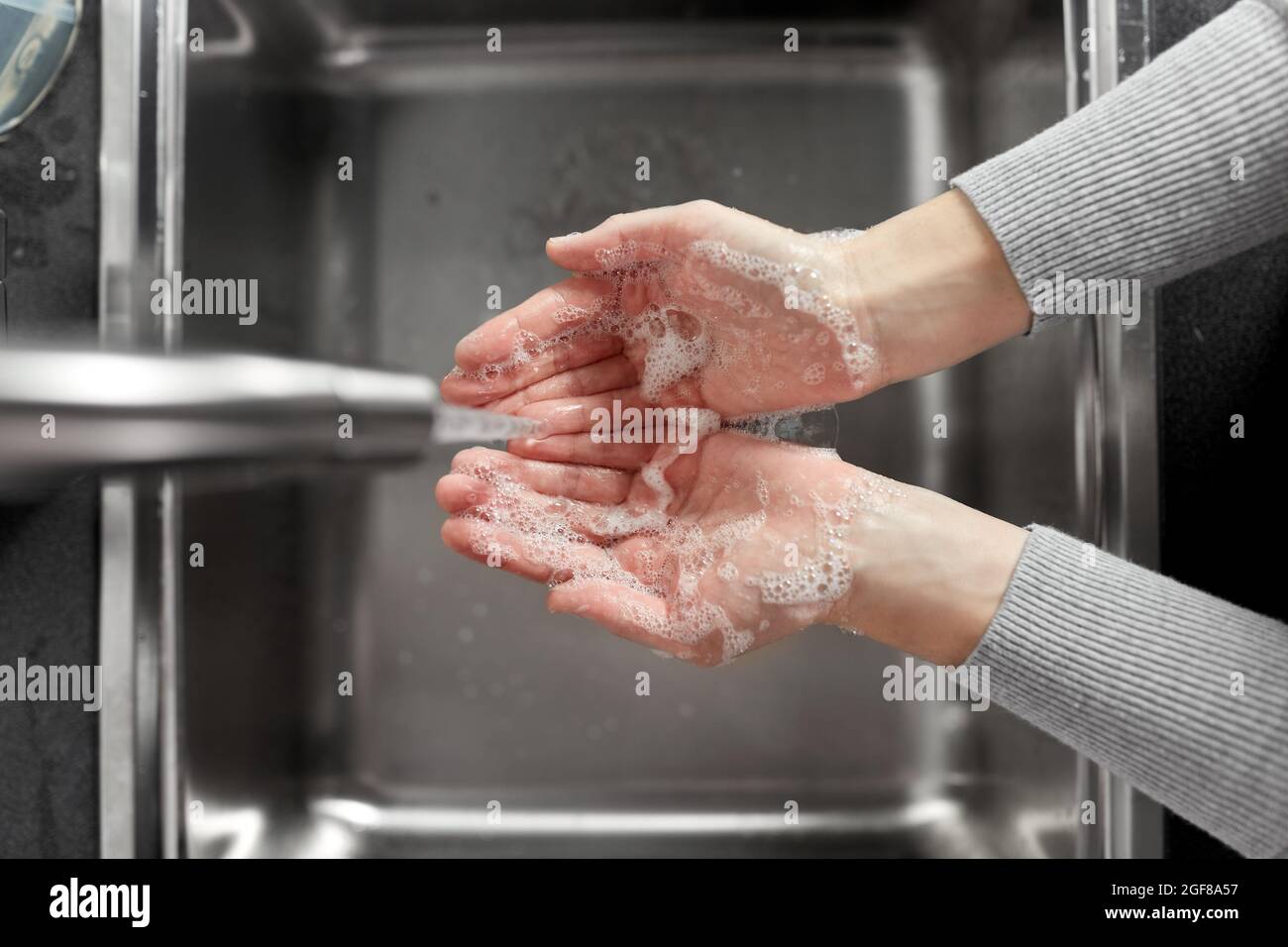 donna lavando le mani con sapone in cucina Foto Stock