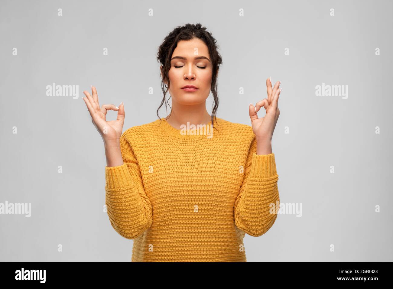 giovane donna con naso trafitto meditating Foto Stock