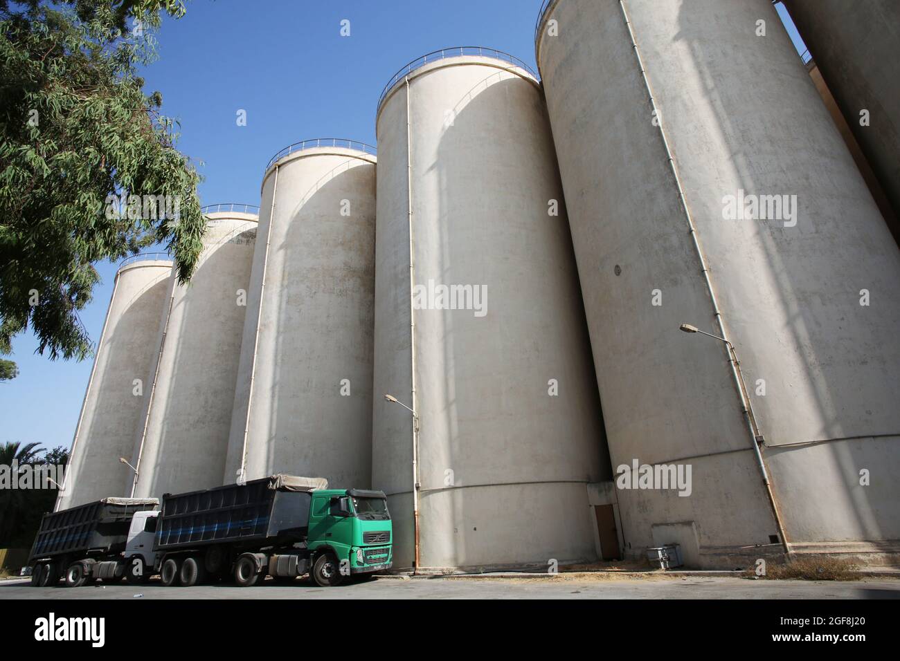 Tunisi, Tunisia. 23 Agosto 2021. Camion visto parcheggiato di fronte ai silos di grano a Manouba Governorate.The raccolto di cereali in Tunisia si trova a 16.4 milioni di quintali questa stagione, Tunis Afrique Presse (TAP/Official) ha detto, citando il ministero dell'agricoltura tunisino. Sul fronte della logistica, 176 centri di raccolta sono stati convalidati su 186 distribuiti in tutto il paese, e 7.9 milioni di quintali di cereali raccolti. Credit: SOPA Images Limited/Alamy Live News Foto Stock