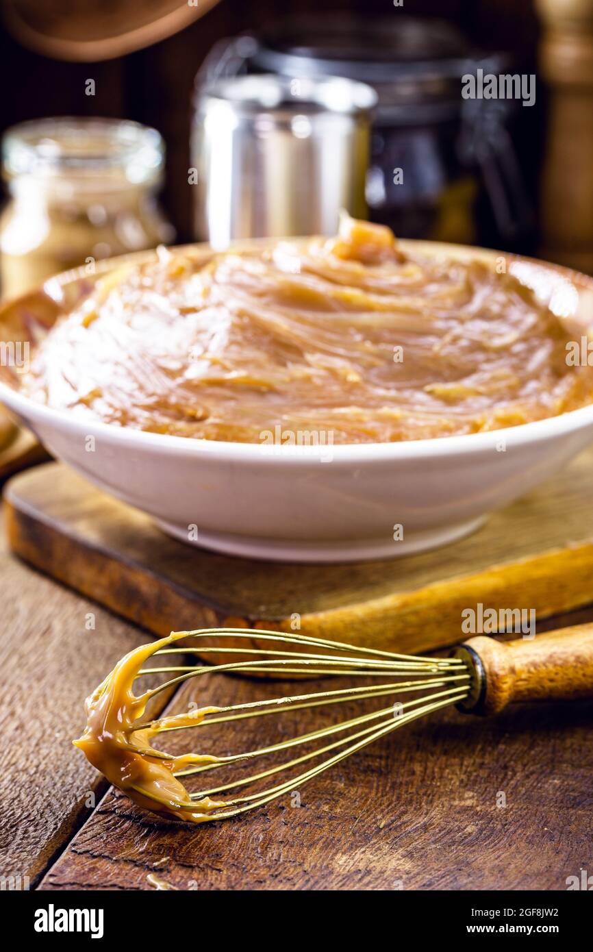 Frusta rustica, strumento da cucina con dolce sullo sfondo Foto Stock