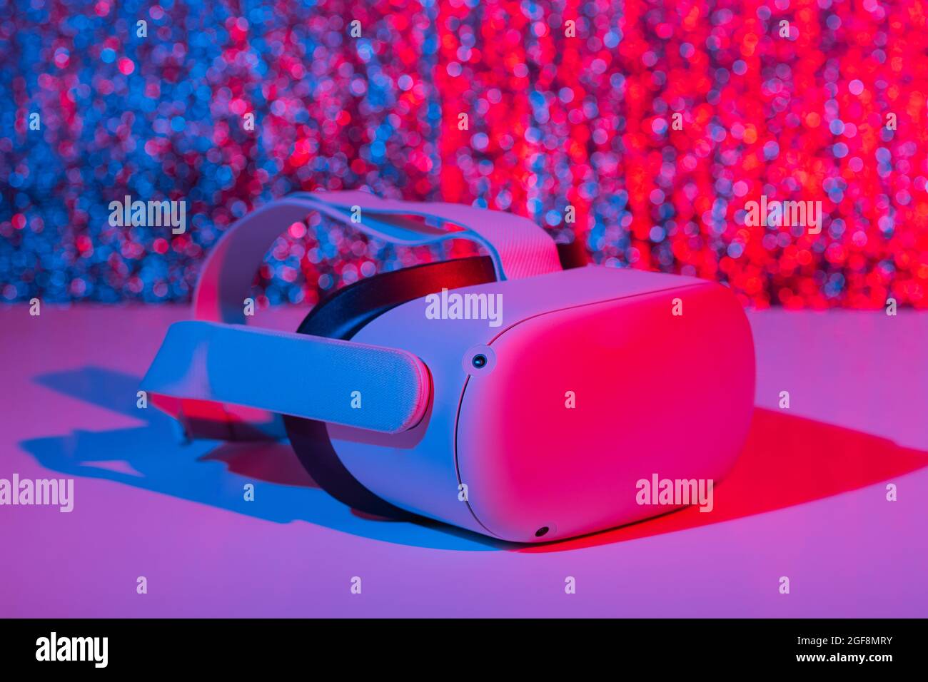 Casco per realtà virtuale su sfondo bianco con luce al neon. Realtà virtuale, futuro, gadget, concetto di tecnologia. Foto Stock