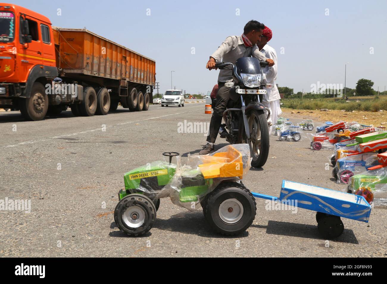 Beawar, Rajasthan, India, 24 agosto 2021: Venditore di strada che vende i giocattoli del veicolo mentre i veicoli pesanti passano sulla Ahmedabad-Delhi National Highway in Beawar. Credit: Sumit Saraswat/Alamy Live News Foto Stock
