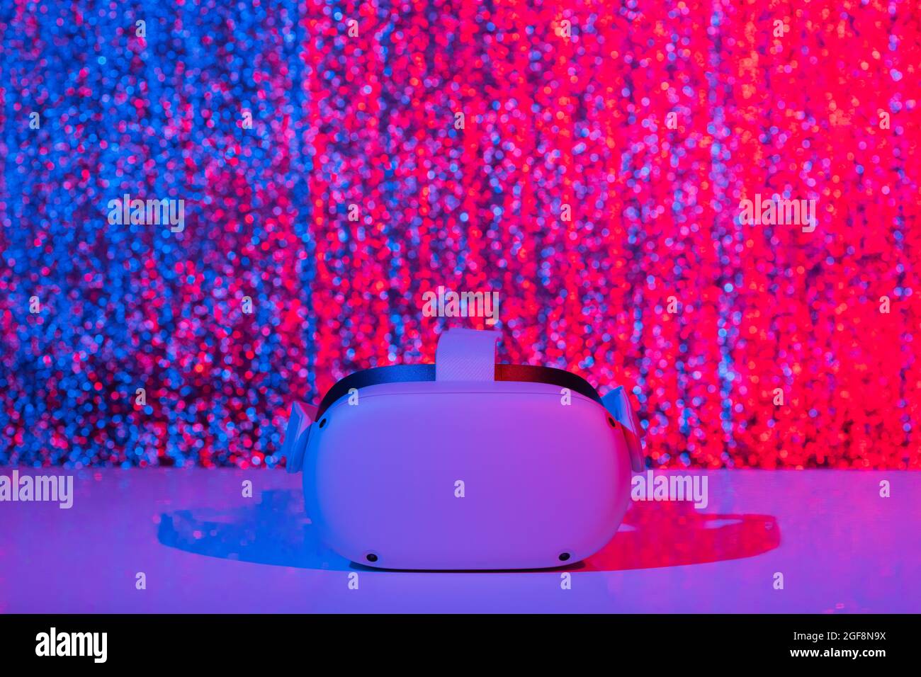 Casco per realtà virtuale su sfondo bianco con luce al neon. Realtà virtuale, futuro, gadget, concetto di tecnologia. Foto Stock