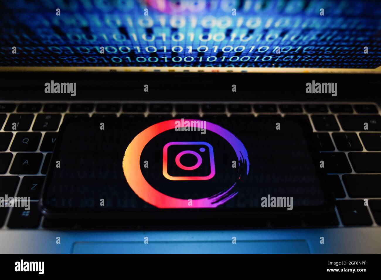 Portogallo. 24 agosto 2021. In questa figura è illustrato un logo Instagram visualizzato su uno smartphone con codice binario sullo schermo di un computer portatile. Credit: SOPA Images Limited/Alamy Live News Foto Stock