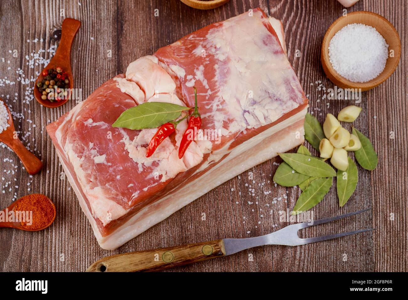 Un pezzo di pancia di maiale con aglio su sfondo di legno. Foto Stock