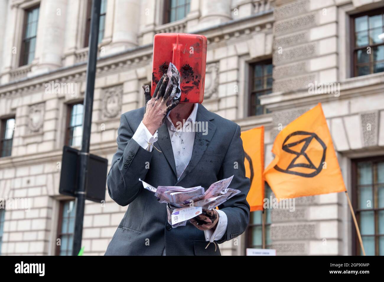 Londra, Regno Unito. 24 agosto 2021. Un uomo con una latta di petrolio sulla sua testa ondeggia falsi soldi durante una ribellione di estinzione XR Cymru Action ha una protesta contro il cambiamento climatico, il riscaldamento globale, che prevede di colpire la causa alla radice della crisi climatica ed ecologica e di chiedere al governo di cedere alle società di combustibili fossili. (Foto di Dave Rushen/SOPA Images/Sipa USA) Credit: Sipa USA/Alamy Live News Foto Stock