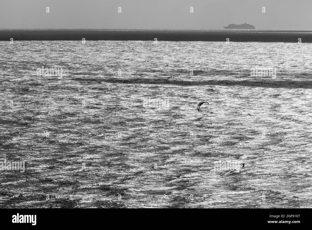 Un kite-surfer solista solleva dall'acqua durante le buone condizioni a Ramsgate mentre una grande nave viaggia più lontano verso il mare, Ramsgate, agosto 2021 Foto Stock