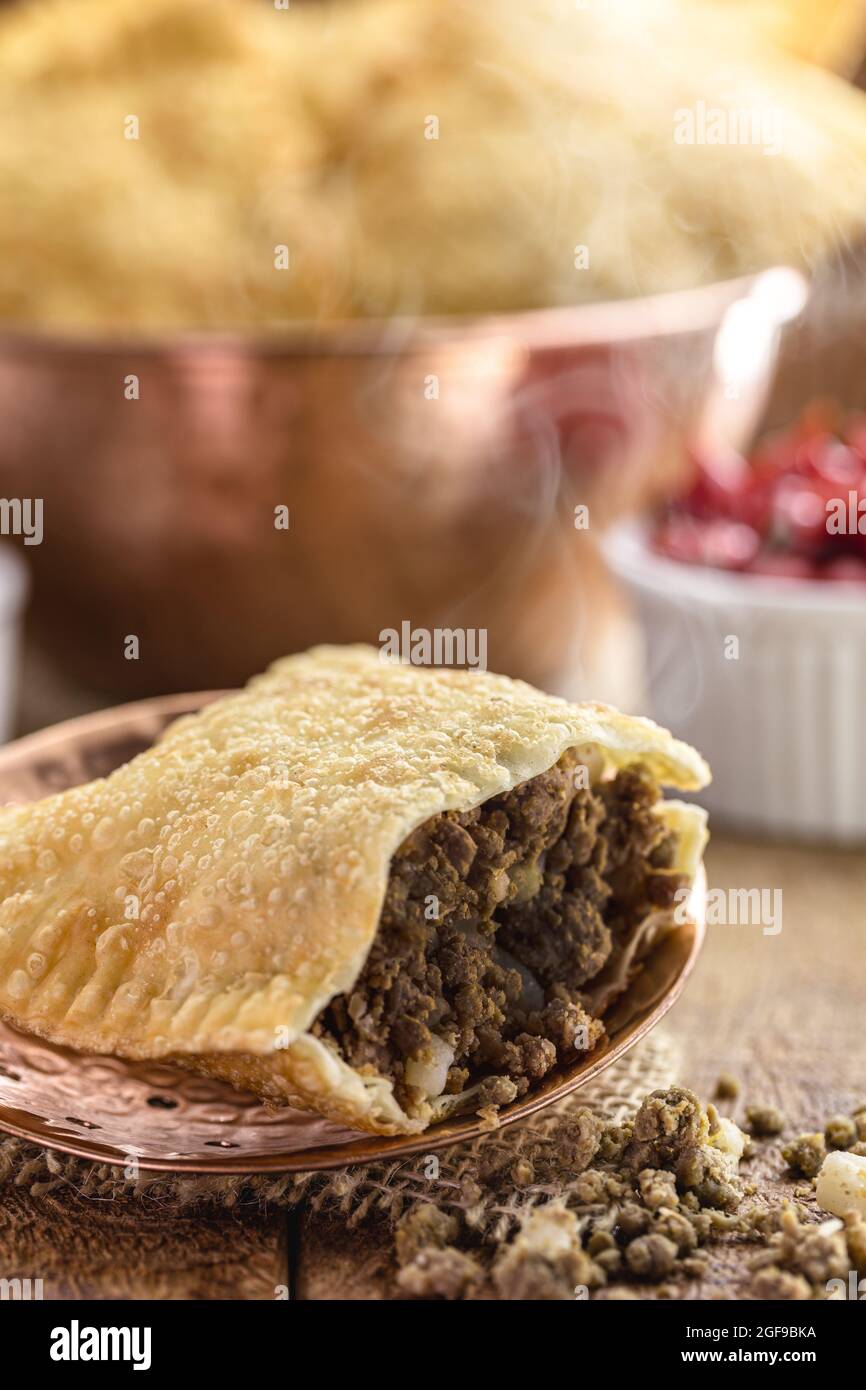 Pasta fritta ripiena di carne macinata e patate, salsa calda servita calda. Foto Stock