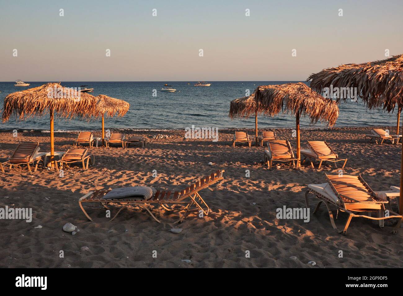Ombrello di paglia con poltrona e Mar Egeo sulla spiaggia di sabbia durante  l'ora d'oro a Rodi. Bellissimo resort greco con Shore in Grecia Foto stock  - Alamy
