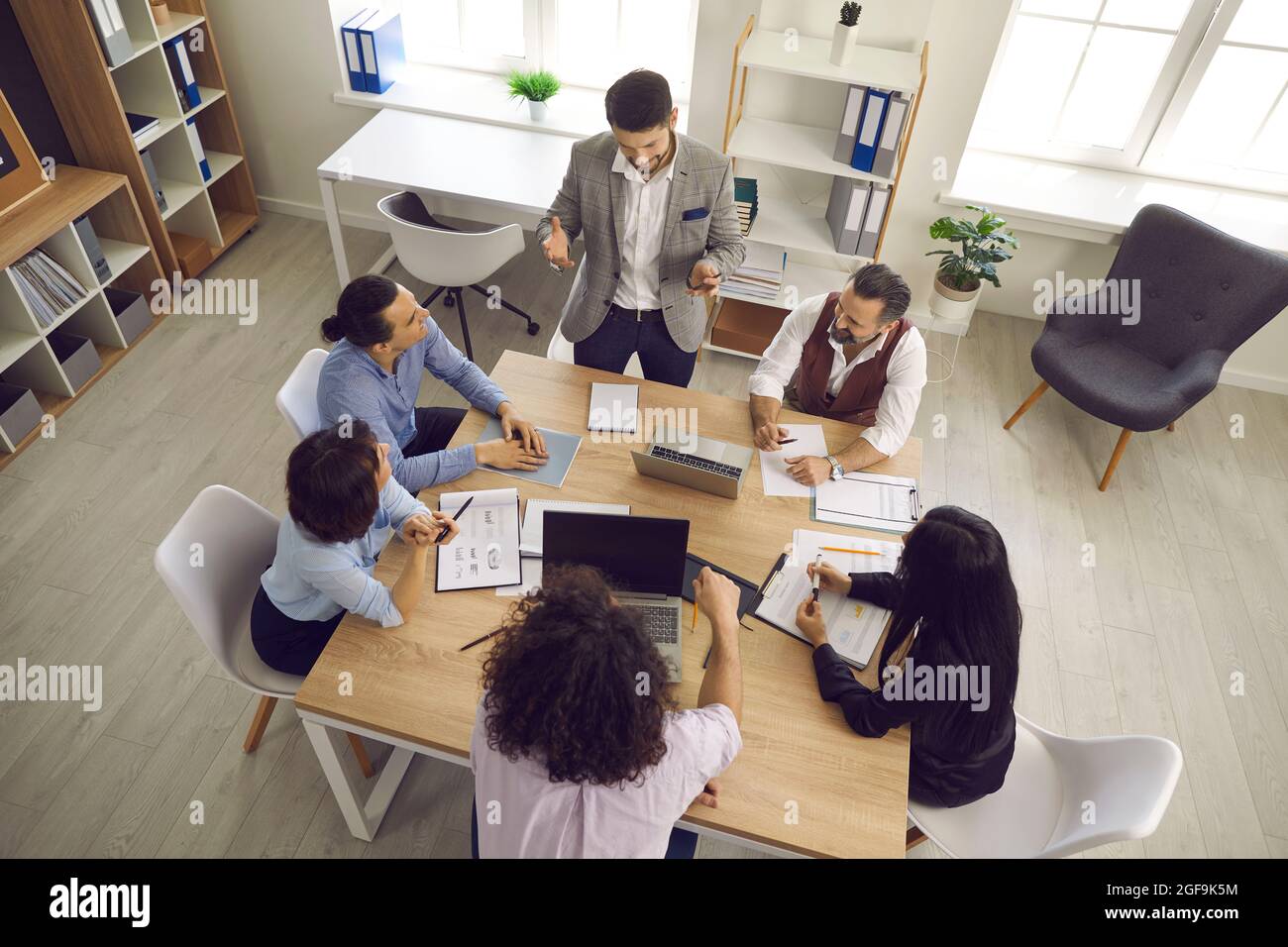 Team di uomini d'affari che hanno una discussione durante una riunione intorno al tavolo dell'ufficio Foto Stock