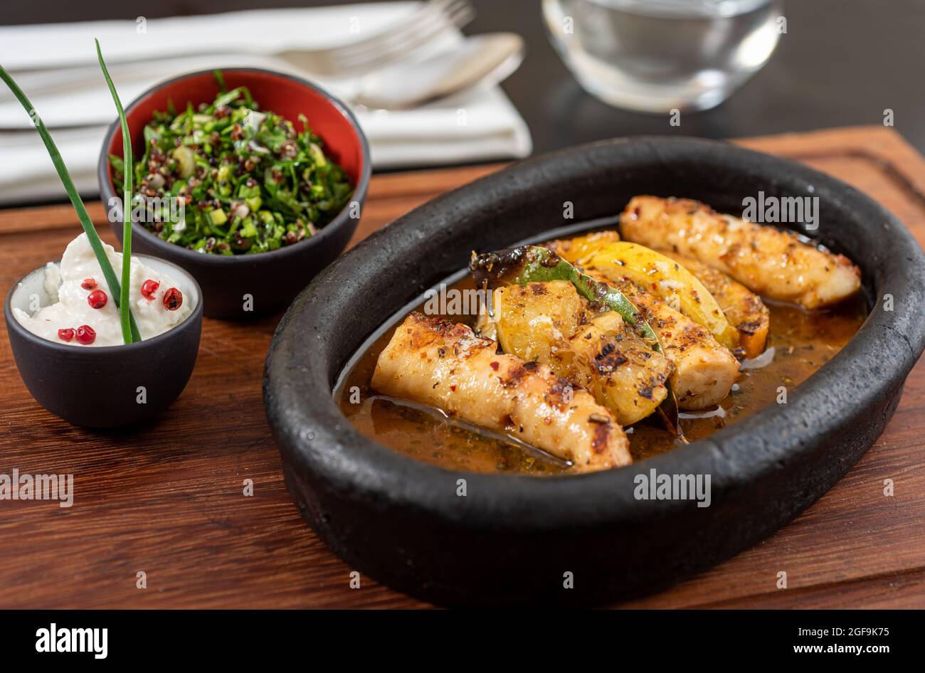 Polpo alla griglia con insalata di quinoa su piastra di pietra nera. Foto Stock