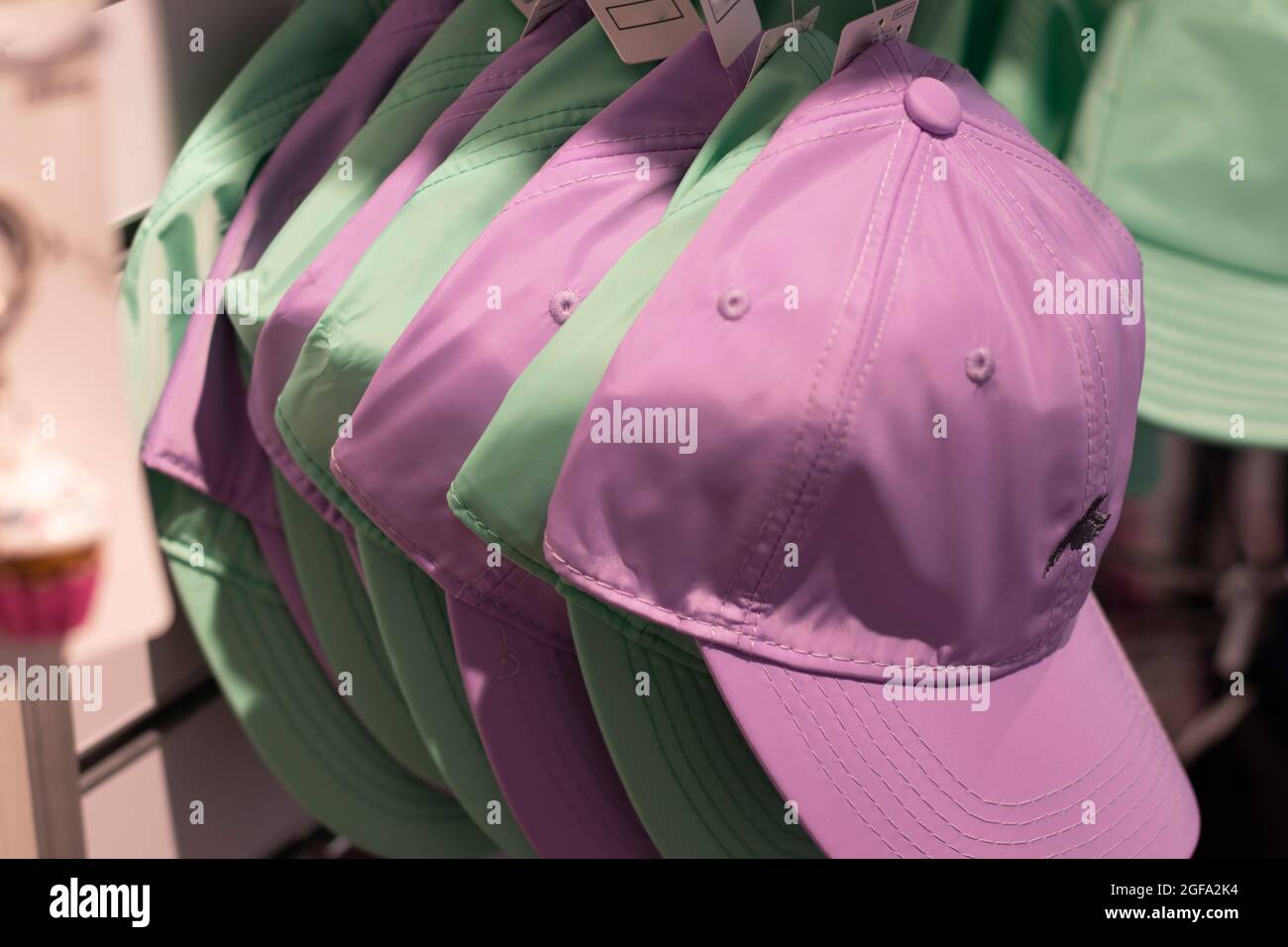 Berretti da baseball verdi e rosa appesi su una rastrelliera. Foto Stock