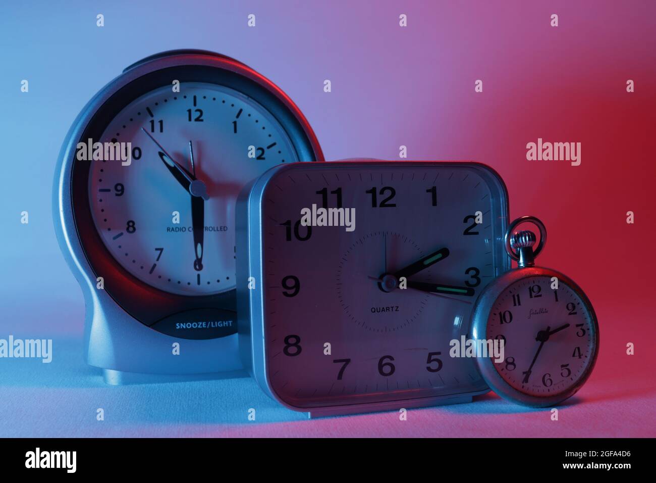 Orologi analogici illuminati da luce blu e rossa Foto Stock