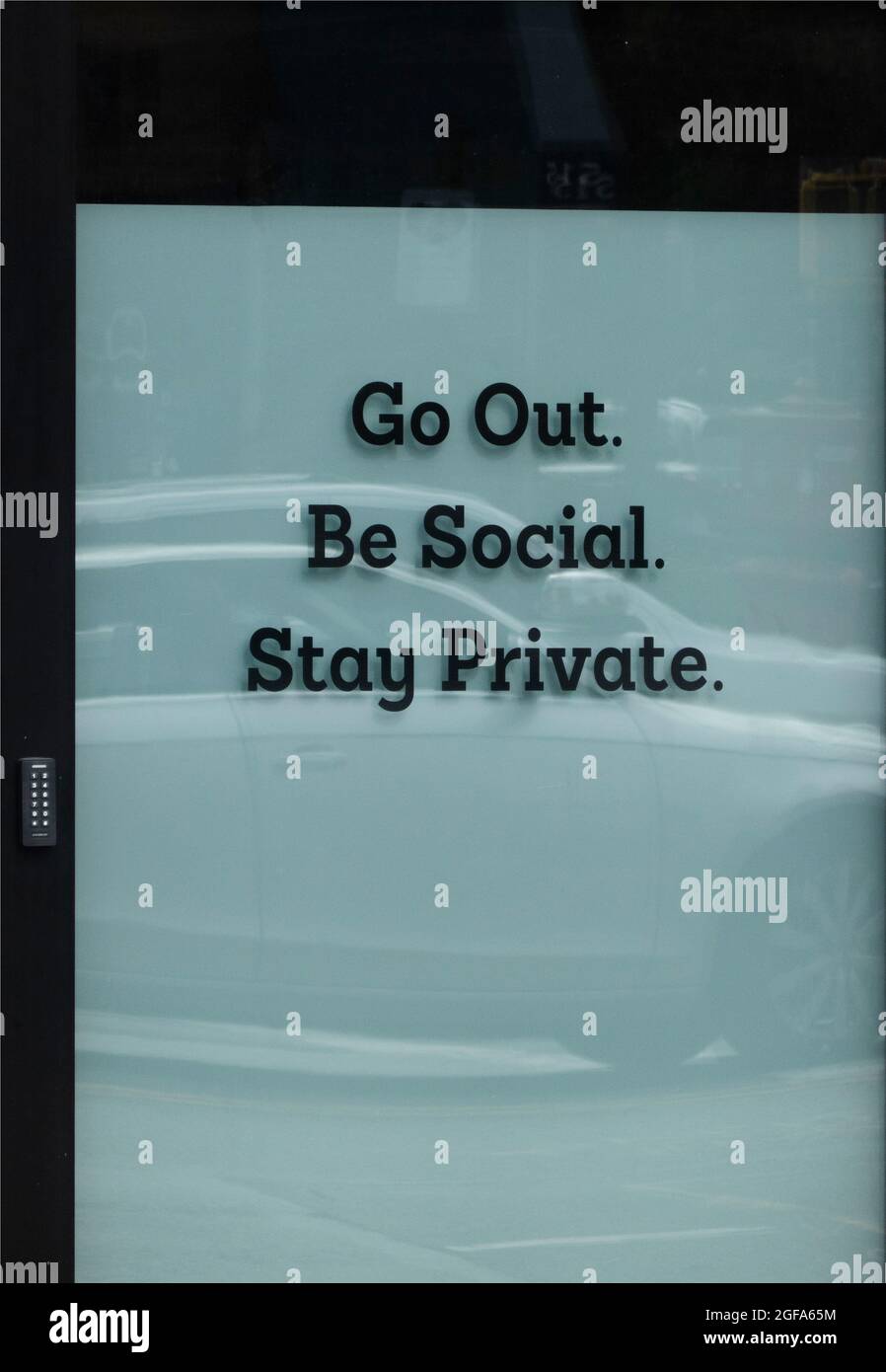 Vai fuori essere sociale soggiorno privato segno in finestra Manhattan NYC Foto Stock