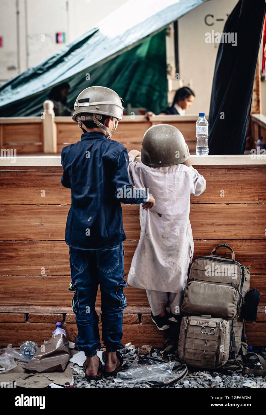 Kabul, Afghanistan. 24 agosto 2021. I bambini afghani giocano con i caschi militari in attesa di evacuazione all'Aeroporto Internazionale Hamid Karzai durante l'operazione Rifuge Allees 24 agosto 2021 a Kabul, Afghanistan. Credit: Planetpix/Alamy Live News Foto Stock