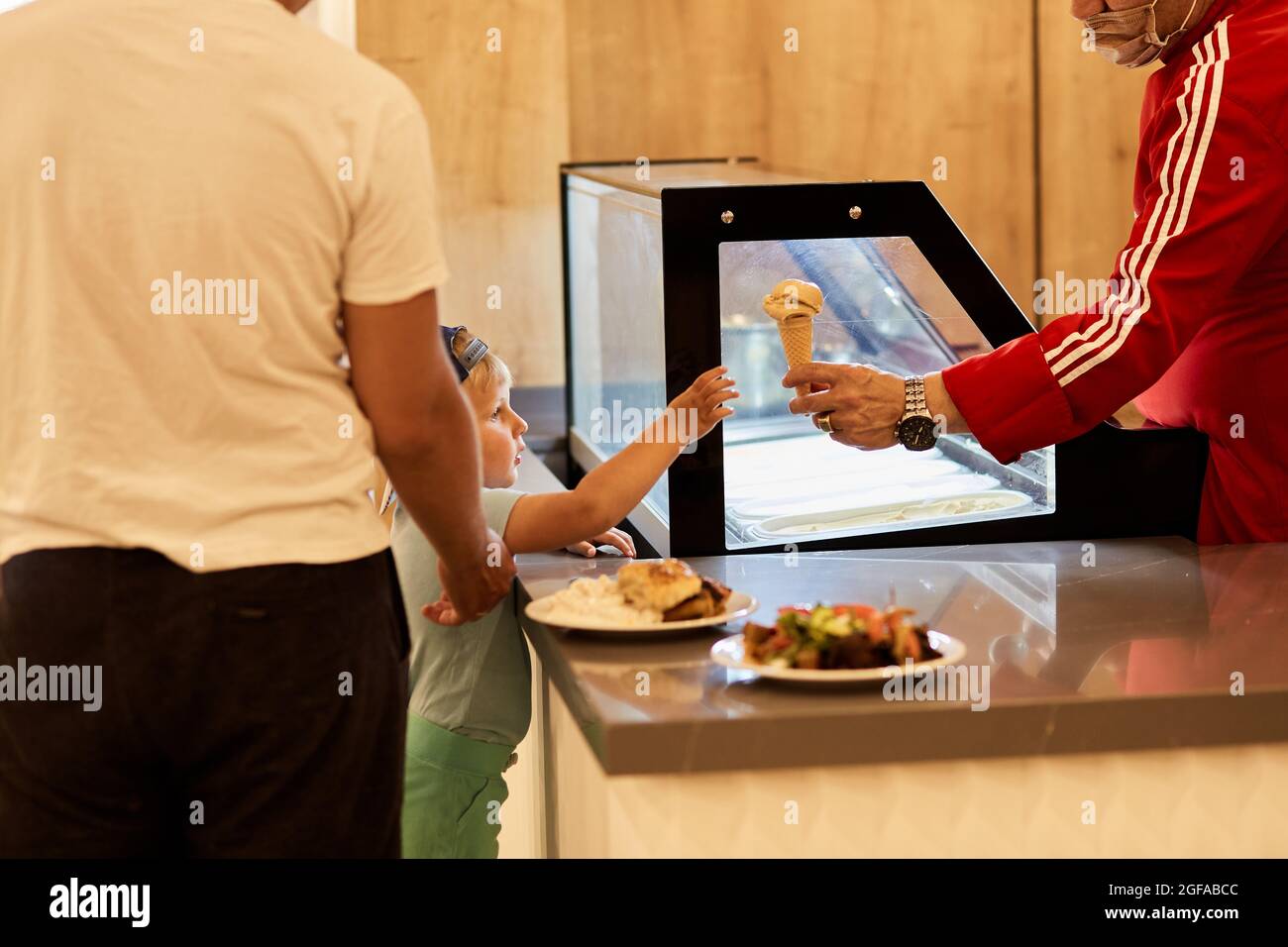 Il cameriere in abiti turchi serve gelato al bambino. Felice infanzia. Padre e figlio. Foto di alta qualità Foto Stock