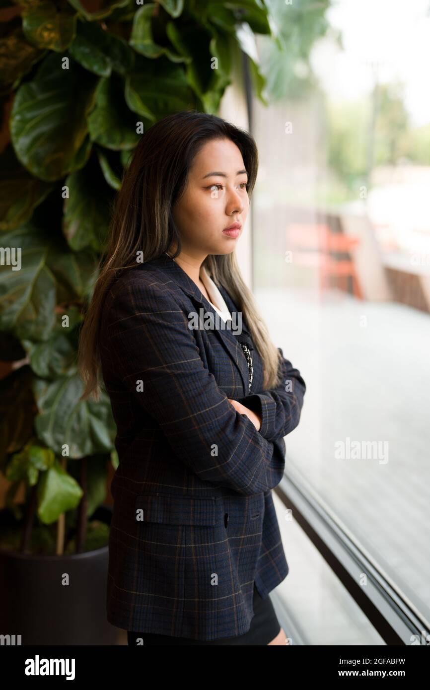 Giovane Asian donna Ufficio lavoratore / Data Scientist guardando fuori finestra Foto Stock