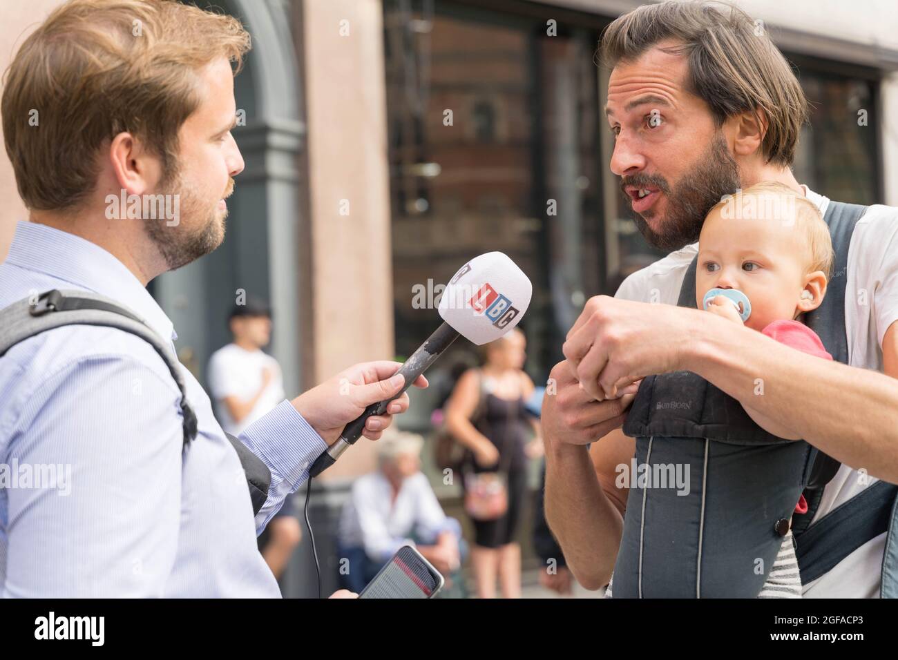 Cambridge Circus, Londra, Regno Unito. 24 agosto 2021. I manifestanti del cambiamento climatico dalla ribellione di estinzione che siede a Cambridge Circus , bloccando Charing Cross Road lungo la strada per Trafalgar Square. LBC news intervistando un uomo con il bambino . Credit: Xiu Bao/Alamy Live News Foto Stock