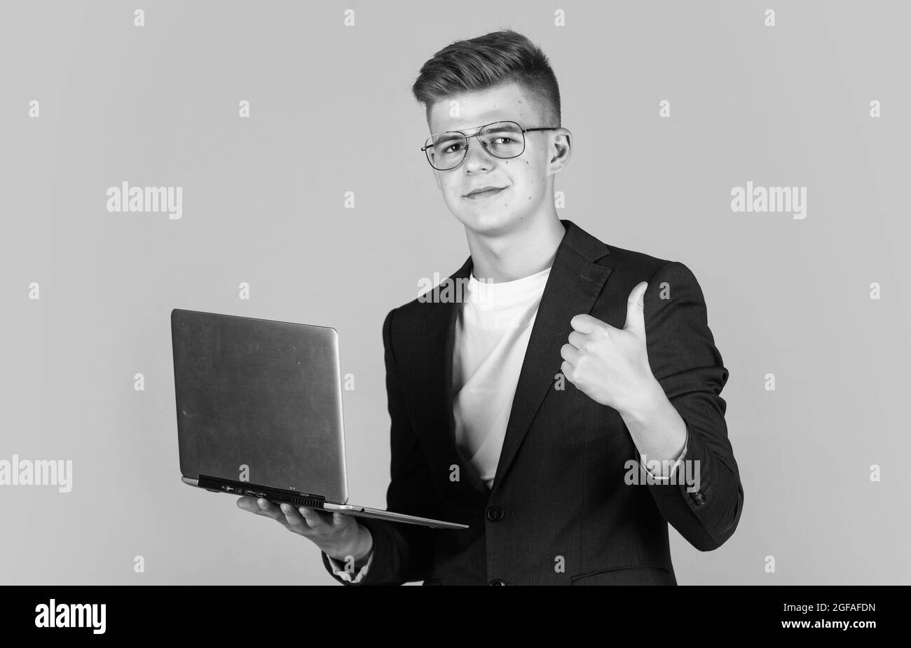 teen boy indossare abiti formali e occhiali utilizzare computer portatile, istruzione Foto Stock