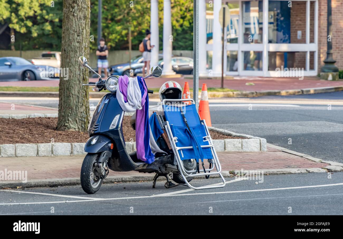 Scooter a motore accatastato con oggetti per la spiaggia parcheggiata a East Hampton, NY Foto Stock