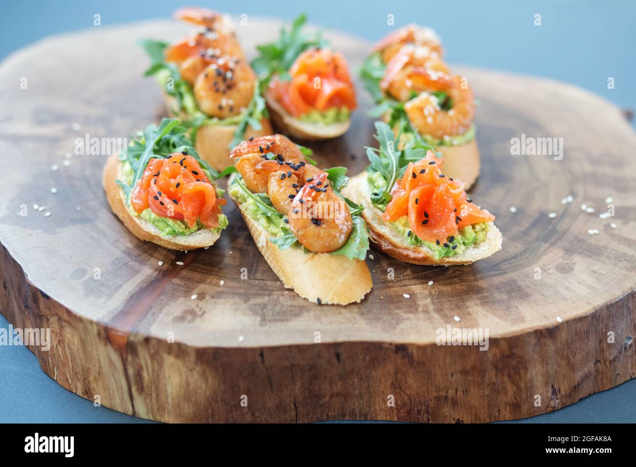 Bruschetta con avocado e salmone, panino di gamberi su un piatto a buffet su un piedistallo di legno Foto Stock