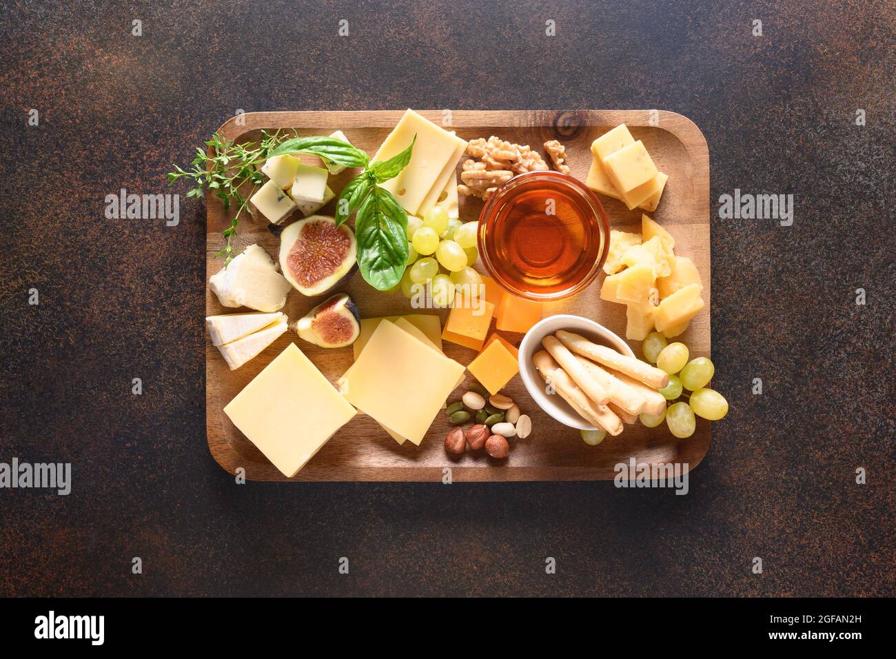 Piatto di formaggi con uva, noci, fichi su sfondo marrone. Vista dall'alto. Aperitivo festivo gourmet per le vacanze. Foto Stock